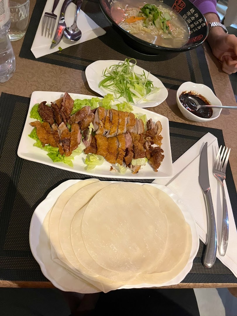 Un canard servi avec des galettes et une soupe de nouilles